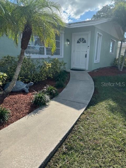 entrance to property with a yard and stucco siding