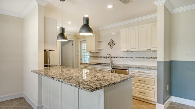 kitchen with decorative light fixtures, a sink, light stone countertops, and white cabinets