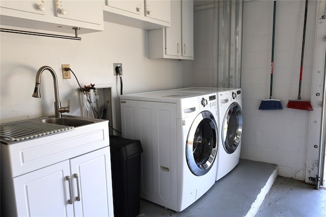 laundry area featuring a sink, washing machine and dryer, cabinet space, and concrete block wall