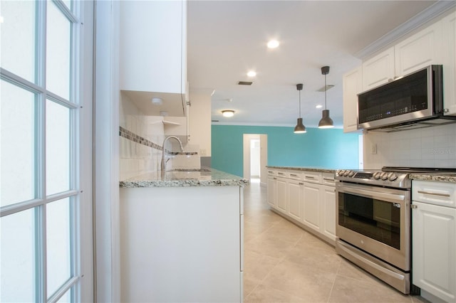 kitchen featuring decorative light fixtures, a sink, stainless steel appliances, white cabinetry, and backsplash