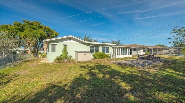 back of house with a sunroom, a fenced backyard, a yard, a patio area, and stucco siding