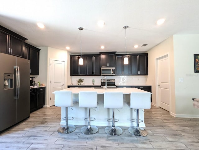 kitchen with sink, a center island with sink, decorative light fixtures, and appliances with stainless steel finishes