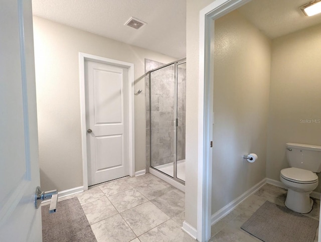 bathroom with tile patterned floors, toilet, and a shower with shower door