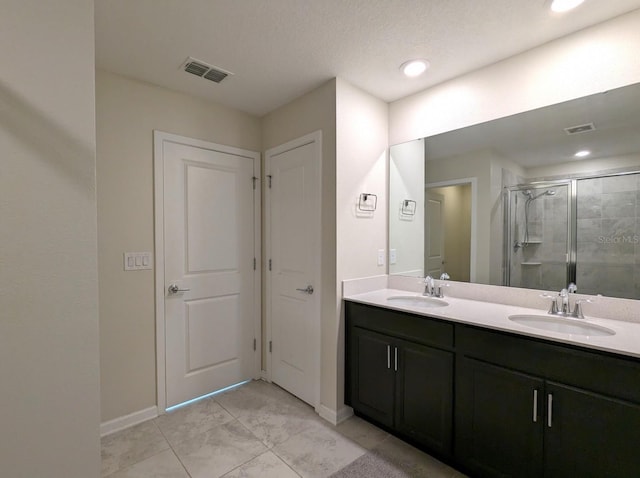 bathroom featuring a textured ceiling, vanity, and a shower with shower door