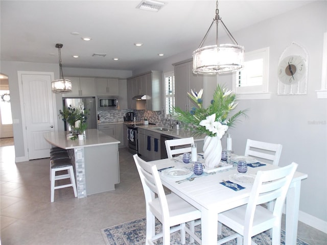 dining area featuring an inviting chandelier, sink, and light tile patterned floors