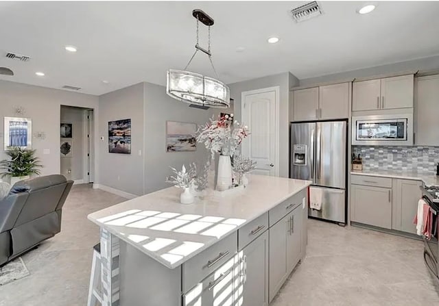 kitchen featuring a kitchen island, decorative light fixtures, gray cabinets, and appliances with stainless steel finishes