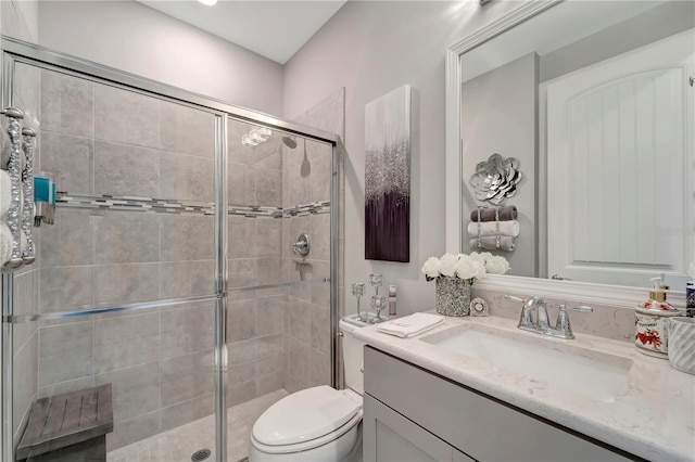 bathroom featuring vanity, toilet, and a shower with shower door