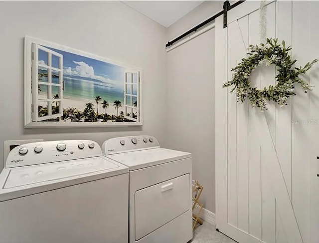 clothes washing area with a barn door and washing machine and clothes dryer