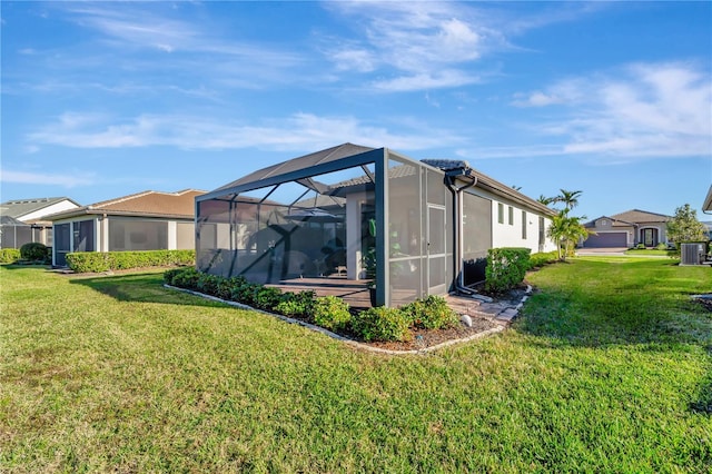 rear view of property with central AC unit, a yard, and glass enclosure