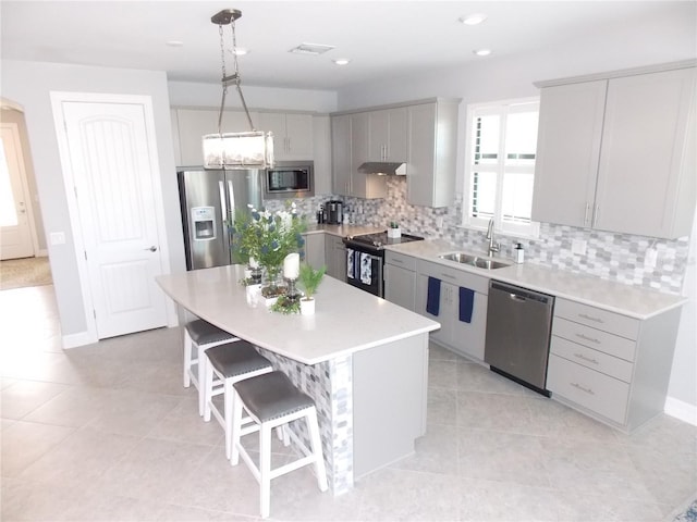 kitchen with sink, gray cabinetry, hanging light fixtures, appliances with stainless steel finishes, and a kitchen island