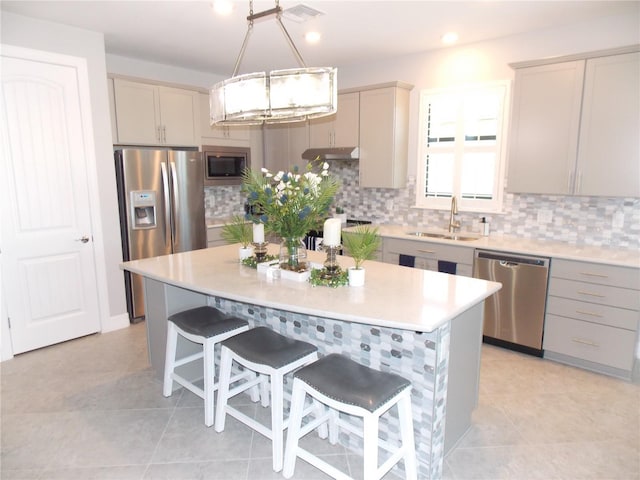 kitchen with appliances with stainless steel finishes, decorative light fixtures, sink, backsplash, and a center island