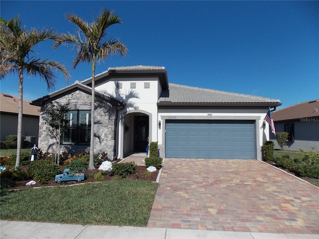 single story home with stucco siding, decorative driveway, stone siding, a garage, and a tiled roof