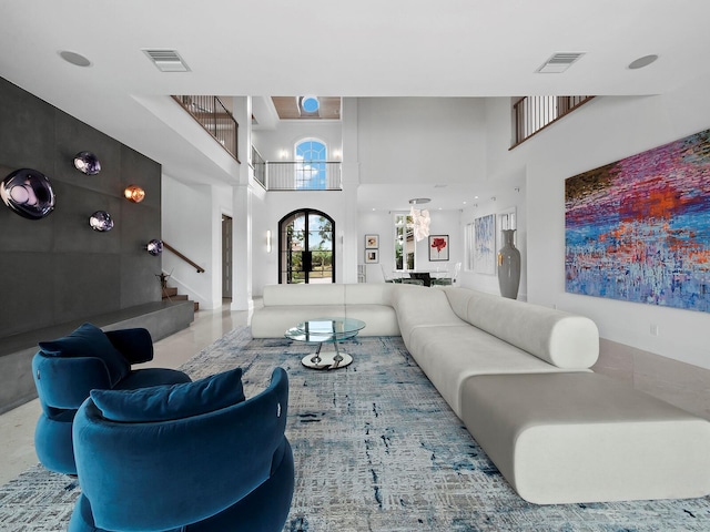 living room with french doors, a towering ceiling, and a notable chandelier