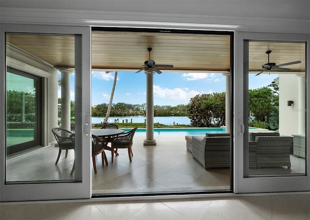 doorway to outside with tile patterned floors, ceiling fan, and a water view