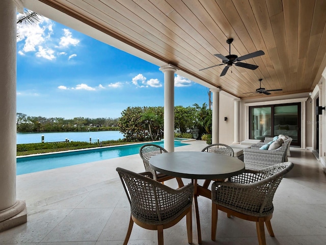 view of swimming pool featuring ceiling fan, a water view, and a patio