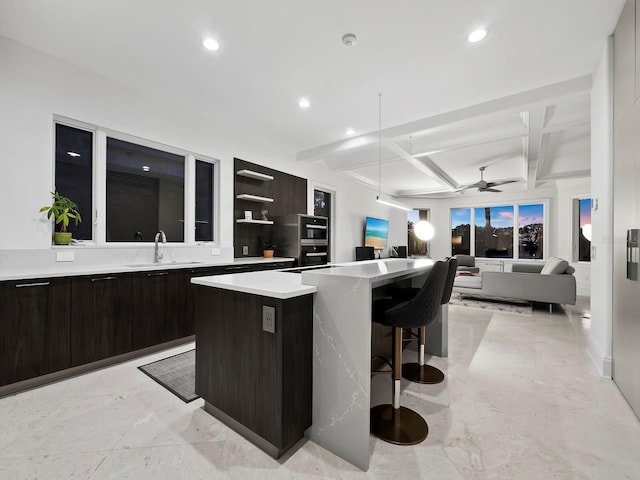 kitchen featuring beam ceiling, a center island, sink, and coffered ceiling