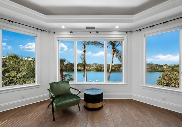 sitting room with a tray ceiling, a water view, and ornamental molding