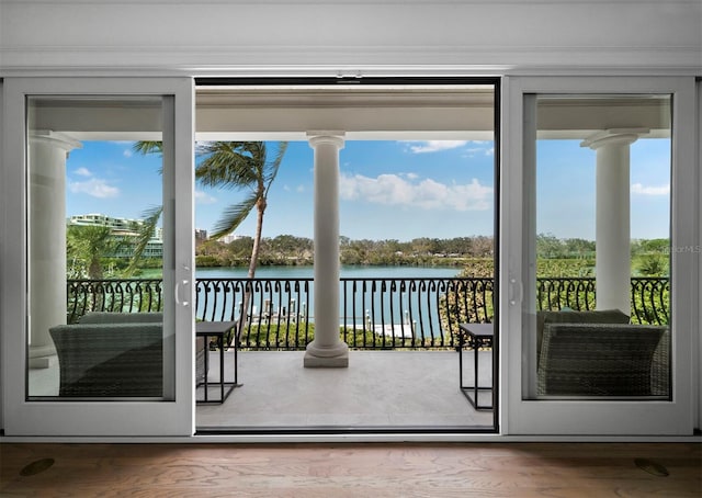 doorway with wood-type flooring, a water view, and crown molding