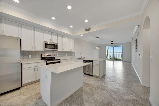 kitchen featuring ceiling fan, stainless steel appliances, kitchen peninsula, decorative light fixtures, and ornamental molding