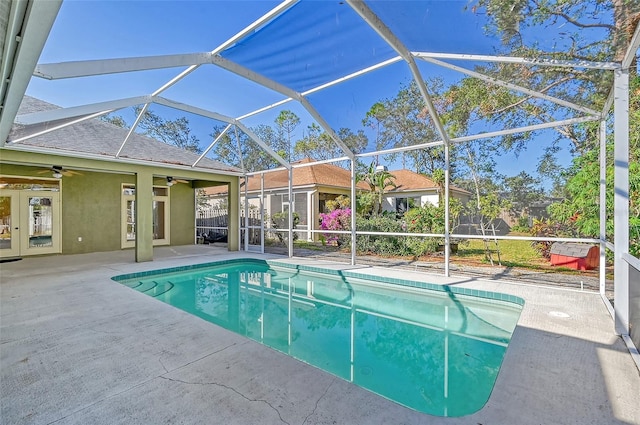 view of swimming pool with ceiling fan, a patio area, and glass enclosure