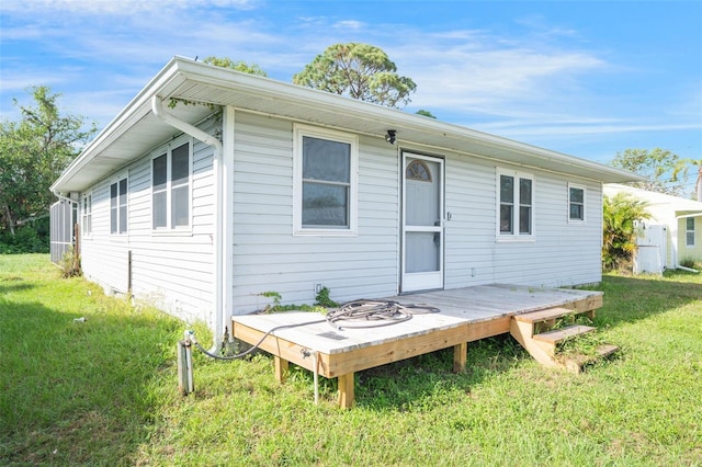 rear view of property featuring a yard and a deck