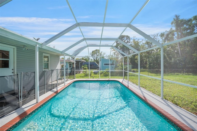 view of swimming pool with a lanai and a lawn