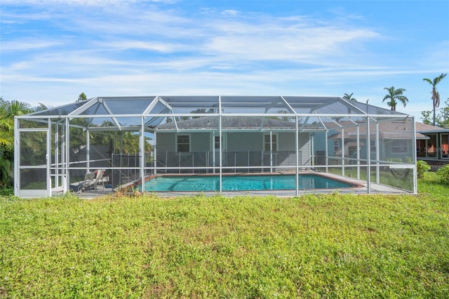 rear view of house featuring a lawn and glass enclosure