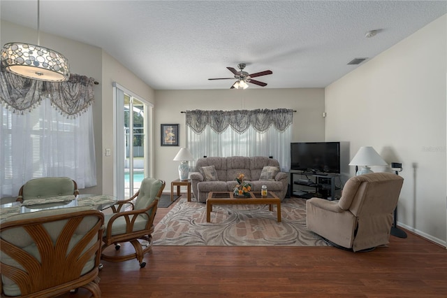 living room with dark hardwood / wood-style floors, ceiling fan, and a textured ceiling