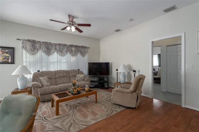 living room featuring ceiling fan, hardwood / wood-style floors, and a textured ceiling