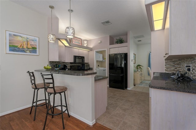 kitchen featuring black appliances, pendant lighting, kitchen peninsula, and backsplash