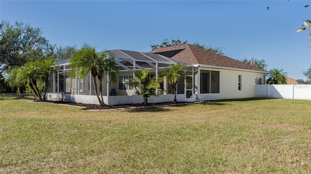 rear view of house featuring a lanai and a lawn