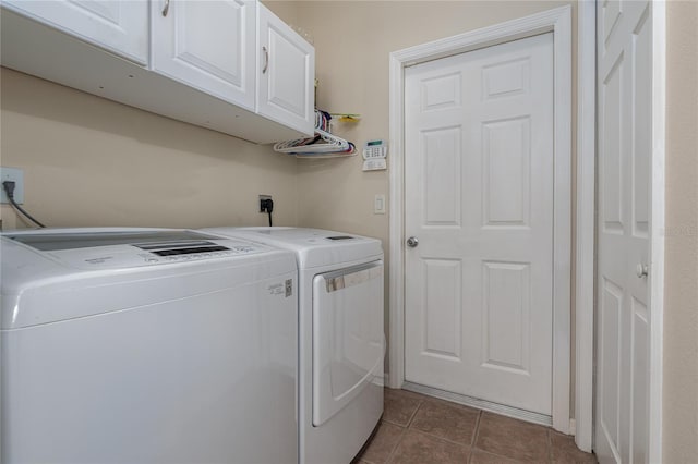 laundry room featuring washer and clothes dryer, cabinets, and dark tile patterned flooring