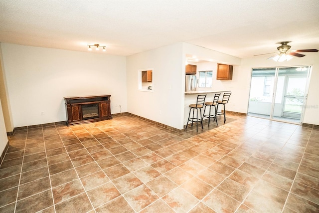 tiled living room with ceiling fan and a textured ceiling