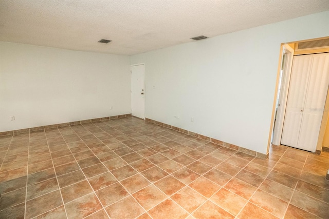 spare room featuring tile patterned flooring and a textured ceiling