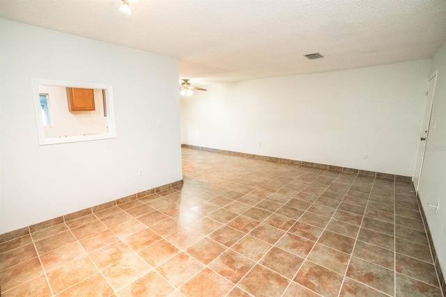 tiled spare room with ceiling fan and a textured ceiling