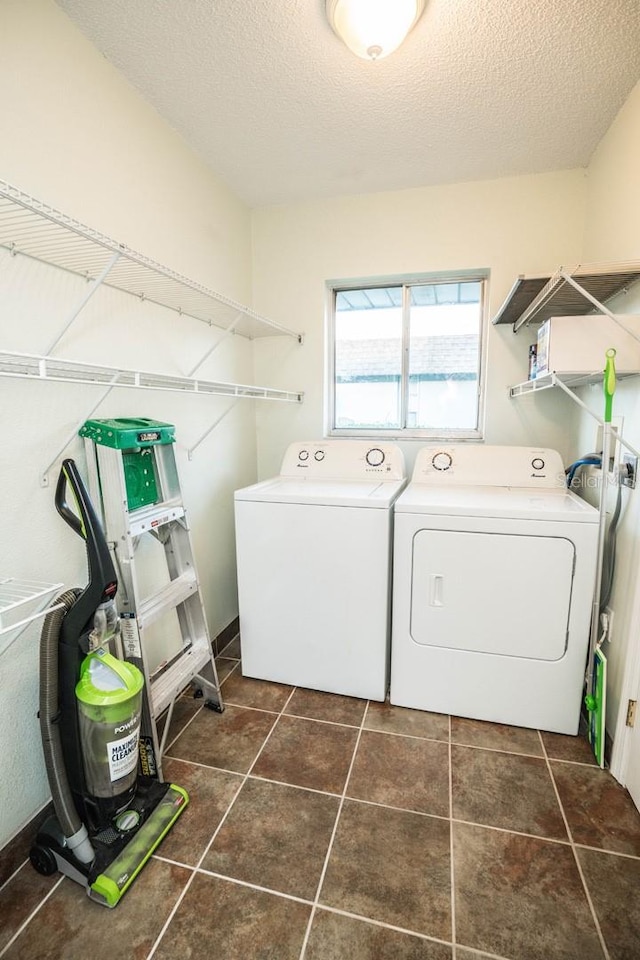 laundry room with separate washer and dryer, dark tile patterned flooring, and a textured ceiling