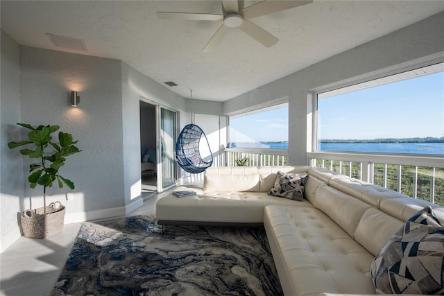 sunroom with a water view and ceiling fan