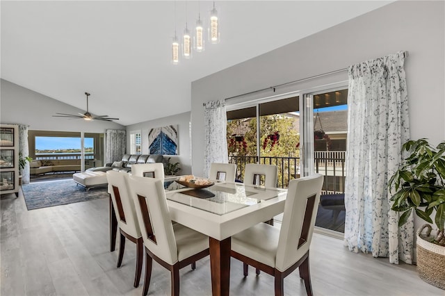 dining room featuring hardwood / wood-style floors, ceiling fan with notable chandelier, and vaulted ceiling