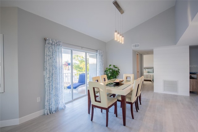 dining room featuring high vaulted ceiling, light hardwood / wood-style flooring, and a notable chandelier