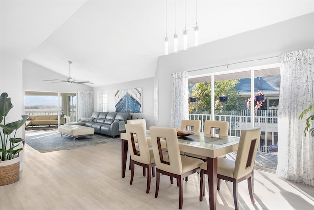 dining space with ceiling fan, light hardwood / wood-style floors, and vaulted ceiling