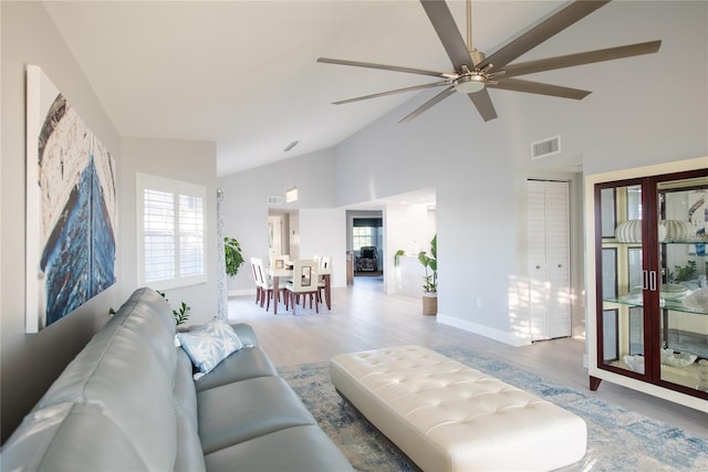 living room with ceiling fan, high vaulted ceiling, and light hardwood / wood-style flooring