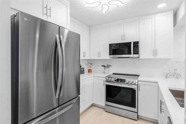 kitchen with decorative backsplash, light stone counters, white cabinetry, and appliances with stainless steel finishes