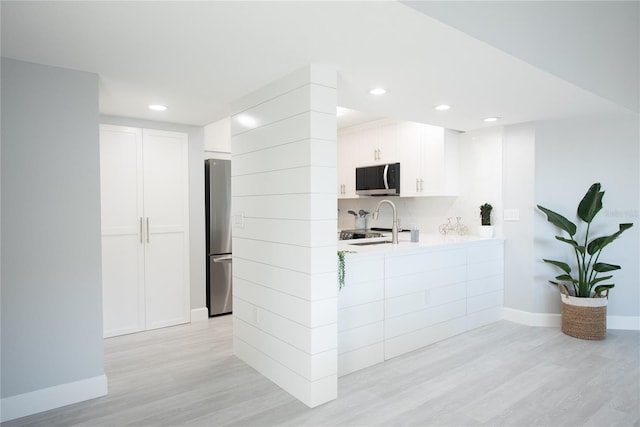 kitchen with sink, white cabinets, stainless steel appliances, and light hardwood / wood-style floors