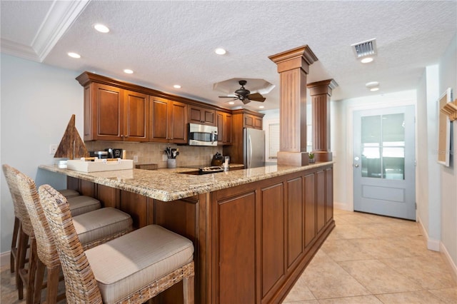 6140 Midnight Pass Rd Unit 407, Sarasota, FL 34242 - kitchen with a textured ceiling, appliances with stainless steel finishes, a kitchen breakfast bar, kitchen peninsula, and light stone counters