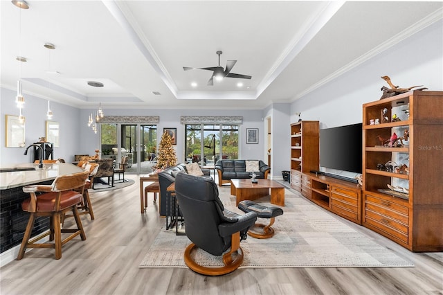 living room featuring french doors, light wood-type flooring, a raised ceiling, and crown molding