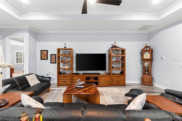 living room featuring light hardwood / wood-style floors, crown molding, and a tray ceiling