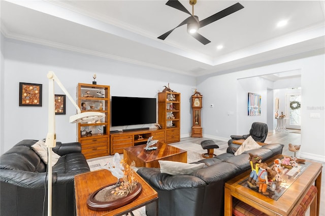 living room featuring a raised ceiling, ceiling fan, and ornamental molding