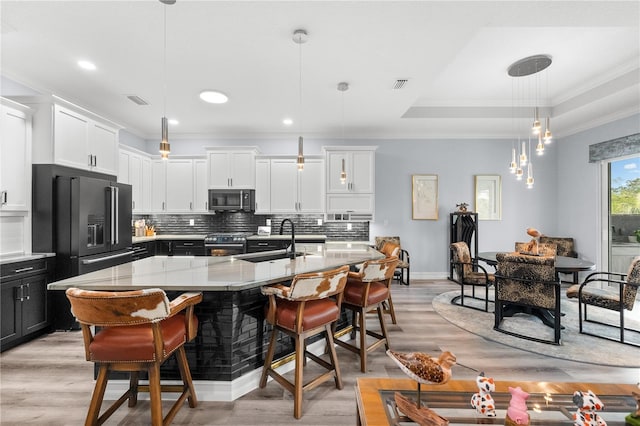 kitchen with a kitchen island with sink, sink, hanging light fixtures, light hardwood / wood-style flooring, and stainless steel appliances