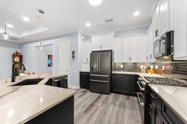 kitchen with white cabinetry, sink, decorative light fixtures, and high end appliances