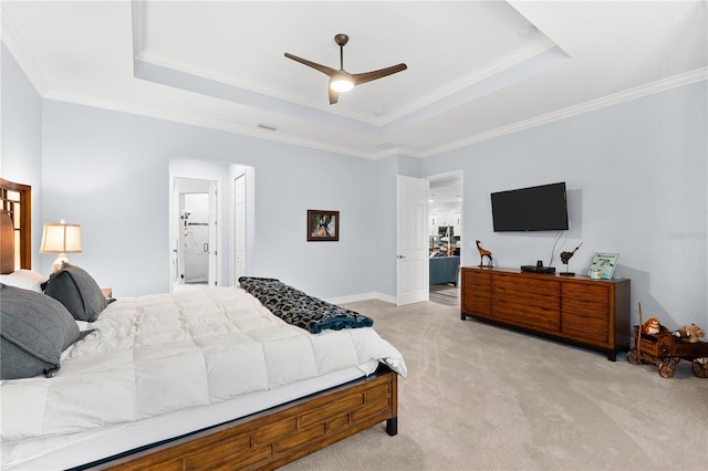 bedroom with ensuite bath, ceiling fan, ornamental molding, a tray ceiling, and light colored carpet